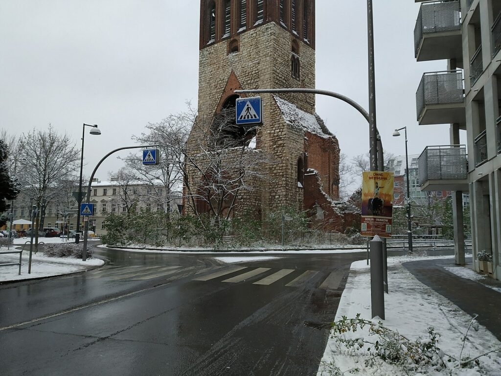 Ein Zebrastreifen mit der Ruine eines Kirchturms im Hintergrund
